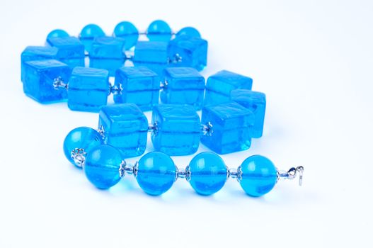 Blue glass beads on white background close up