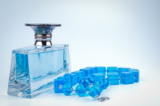 Blue beads and bottle perfume on white