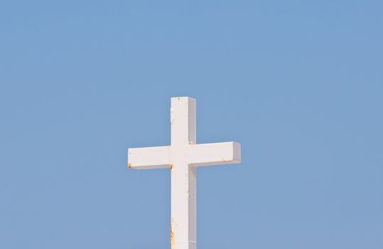 White Christian cross on blue sky background