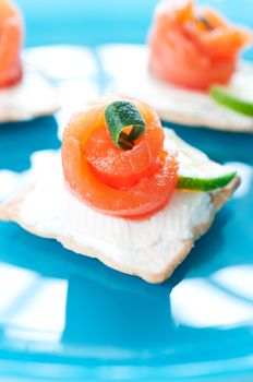 Canapes with smoked salmon and cream cheese on blue background