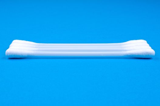 Four cotton buds on blue  background close up