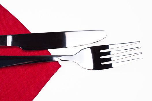 Knife and fork on red tablecloth isolated close up