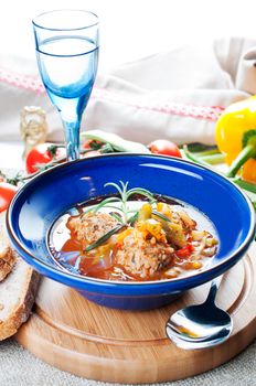 Meatball soup with vegetables on wooden board