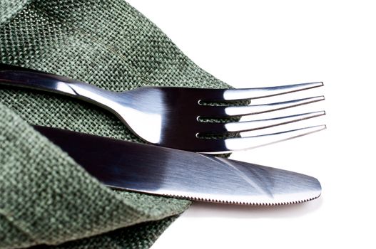Knife and fork on green napkin close up