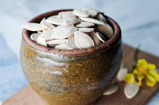 Ceramic bowl full of pumpkin seeds on kitchen table background