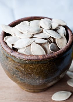 Ceramic bowl full of pumpkin seeds on kitchen table