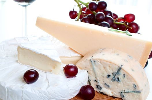 Brie parmesan and blue cheese on grape and red wine background