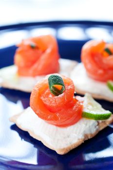 Canapes with smoked salmon and cream cheese on dark blue plate