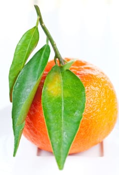 Tangerine with green leaves on a plate close up