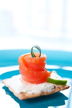 Canapes with smoked salmon on blue background close up