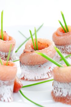 Rolls of marinated herring close up with spring onion