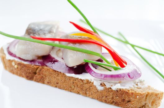 Close up of sandwich with marinated herring bites on rye bread