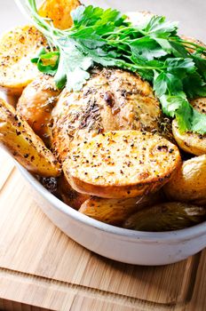 Oven baked potato with pasley in deep white bowl on wooden cutting board