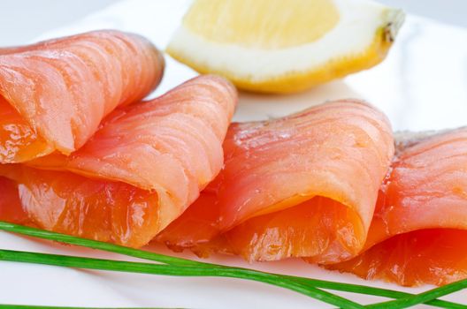 Close up smoked salmon pieces with lemon and chives