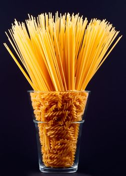 Spaghetti and pasta in vase on black background
