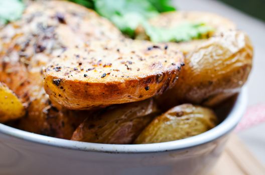 Oven baked spicy potato close up in white bowl