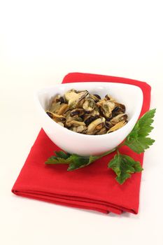 marinated mussels with italian parsley in a bowl on bright background