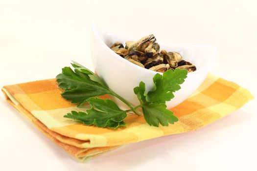 marinated mussels with flat leaf parsley in a bowl on checked napkin