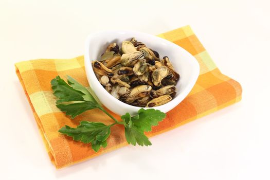 marinated mussels with flat leaf parsley in a bowl on an orange napkin