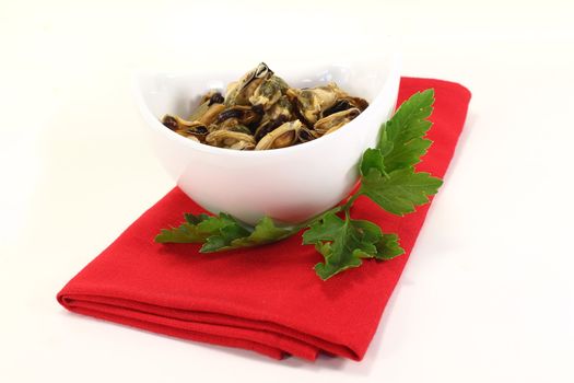 marinated mussels with flat leaf parsley in a bowl on red napkin