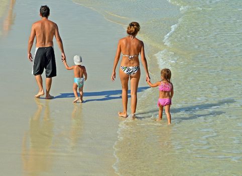 Young couple with their toddler children strolling on southeast florida beach