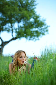 blonde lays and blow on dandelion on hill