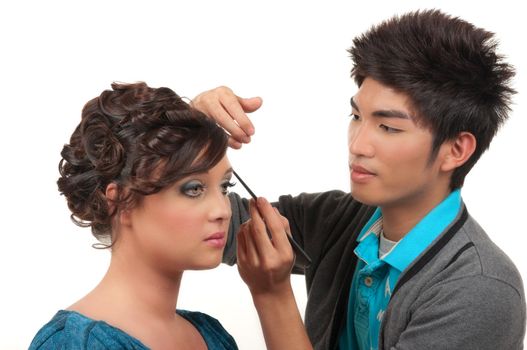 Cosmetics artist doing finishing touches of her customer's hair and make up before her prom, wedding