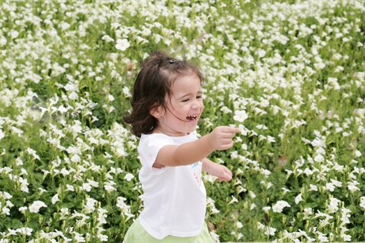 Baby girl happy in a garden of flowers
