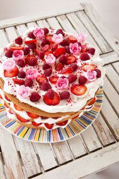 Layered cake decorated with fruit and marzipan flowers viewed from top