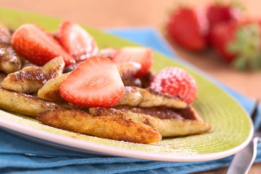 Schupfnudeln (Swabian potato noodles from Southern Germany) with fresh strawberries, cinnamon and sugar powder (Selective Focus, Focus on the lower edge of the strawberry in the front) 