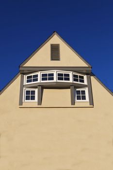 Unique rotunda windows on large beige home wall with dark blue sky