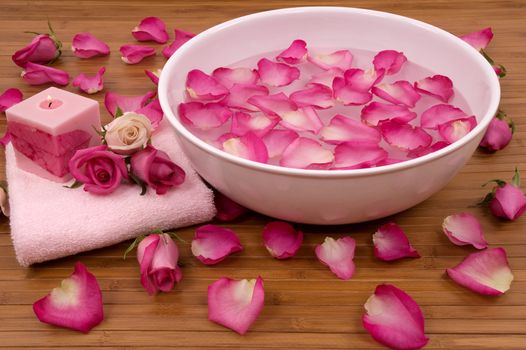 Fresh bright pink roses, petals, candle, and towel in a spa