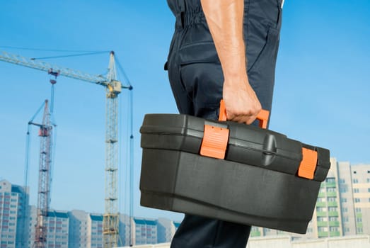 repairman with box of instruments on building background