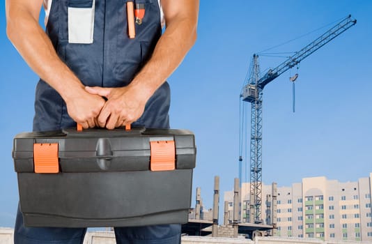 repairman with box of instruments on building background