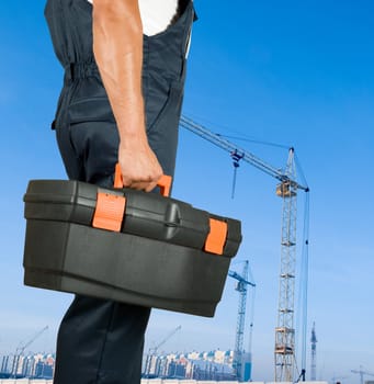 repairman with box of instruments on building background