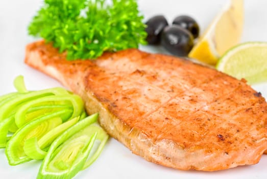 Grilled salmon steak with greens,onion, lemon, lime and olive