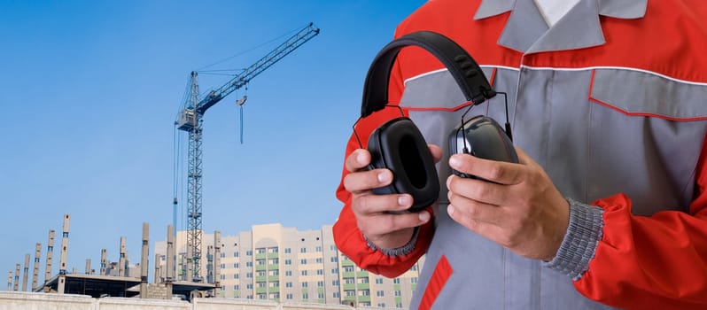 protective headphone at man hands on building background