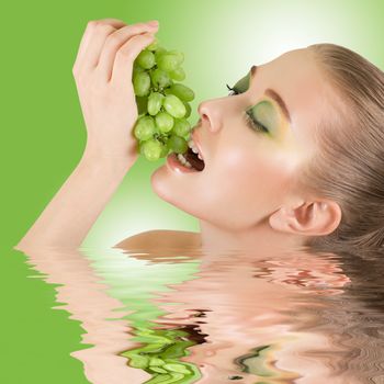 Pretty young woman closeup with grape on green water background