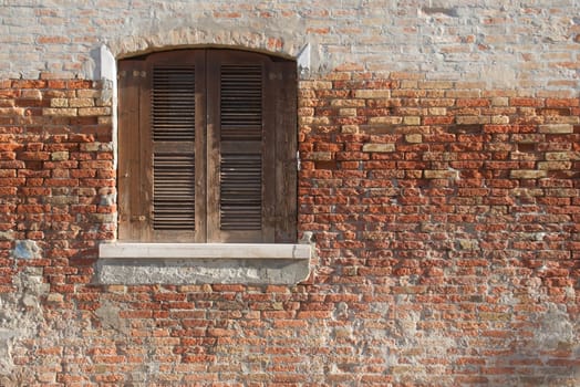 A fragment of an old wall with a window. Photographed in Italy