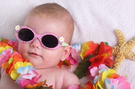 Beautiful baby girl with lei, sun glasses and a starfish on vacation