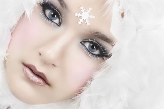 Girl with beautiful make up, white feathers and snow flake