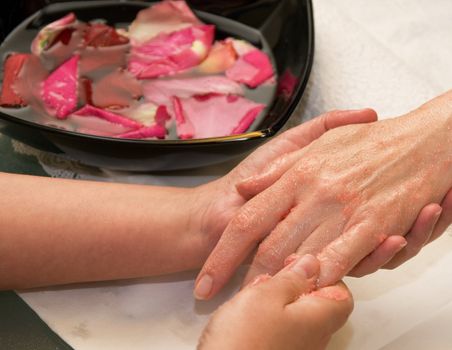 Female hands preparation to manicure at bowl with rose and water