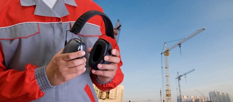 protective headphone at man hands on building background