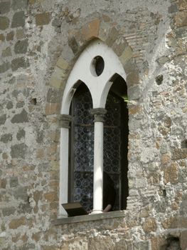 ancient and modern - girl typing on her laptop from a gothic window sill