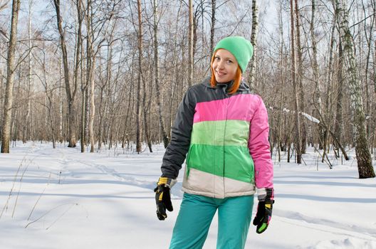 Cheerful woman wearing snowboarding outfit in winter forest