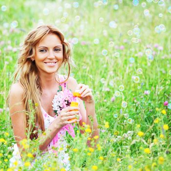  Blonde starts soap bubbles in a green field