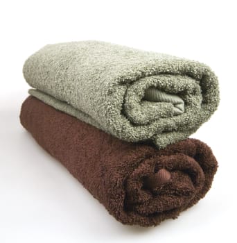 Two rolled fluffy towels on a white background