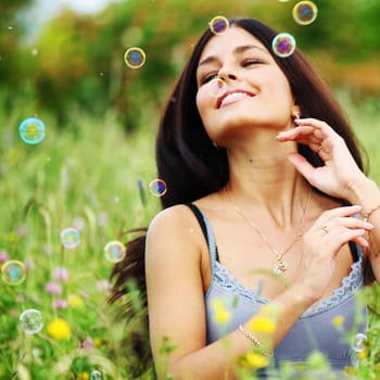  happy woman smile in green grass soap bubbles around