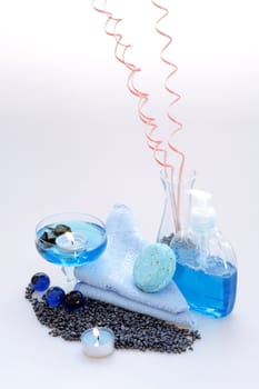 liquid for body care, candles and a blue towel on a white background