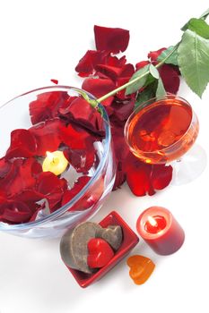 Red rose in an environment of petals and soap and a burning candle on a white background